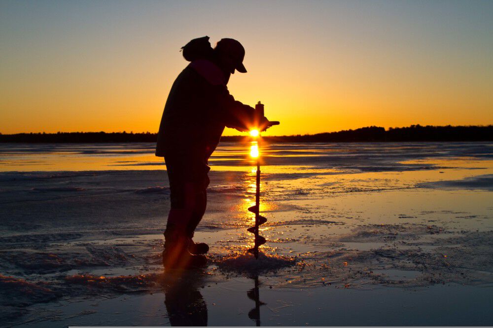 Using a skimmer to remove ice from an ice fishing hole drilled by an ice  auger on a lake in central Michigan, USA Stock Photo - Alamy